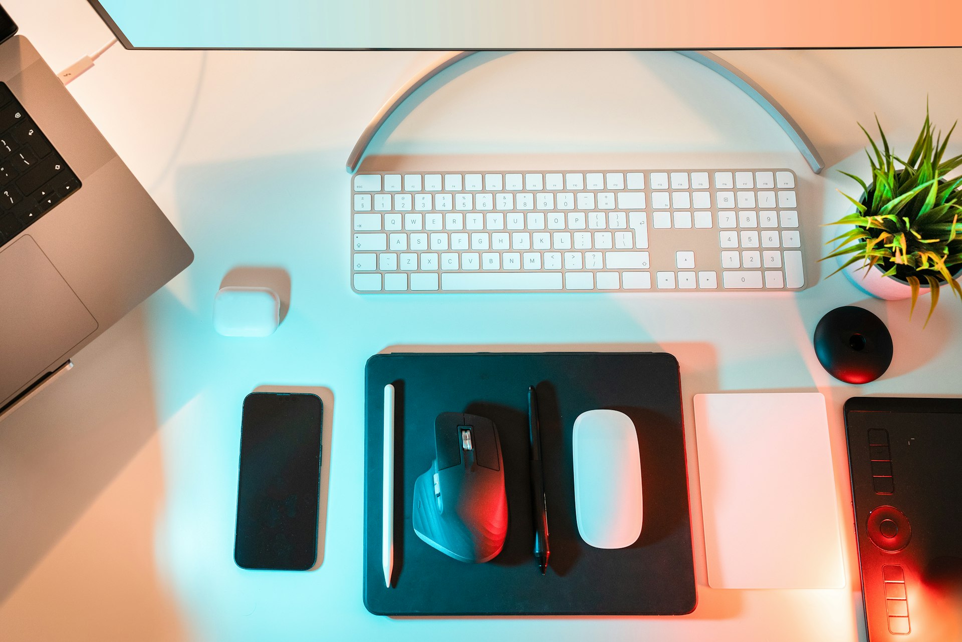 Espacio de trabajo optimizado con soporte y tecnología a tu medida Escritorio con teclado, mouse, stylus y accesorios tecnológicos organizados, representando un entorno de trabajo en TI.